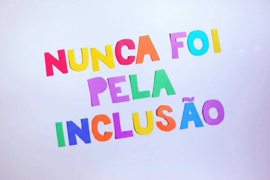 A frase está disposta em três linhas: NUNCA FOI PELA INCLUSÃO As letras apresentam uma inclinação para cima e para a direita, sugerindo que a foto foi tirada em ângulo. As cores das letras, da esquerda para a direita, são: Primeira linha ("NUNCA FOI"): N (vermelho), U (amarelo), N (rosa/magenta), C (laranja), A (amarelo), F (vermelho), O (azul claro), I (amarelo). Segunda linha ("PELA"): P (roxo), E (verde claro), L (roxo), A (verde claro). Terceira linha ("INCLUSÃO"): I (azul claro), N (laranja), C (roxo), L (amarelo), U (azul claro), S (laranja), Ã (roxo), O (amarelo).